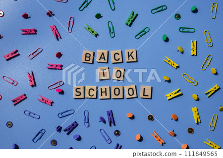 BACK TO SCHOOL message inscription text on wooden blocks on creative colorful blue background with stationery supplies around. Educational greeting announcement for students and teacher. Top view flat BACK TO SCHOOL message inscription text on wooden blocks on creative colorful blue background with stationery supplies around. Educational greeting announcement for students and teacher. Top view flat 111849565