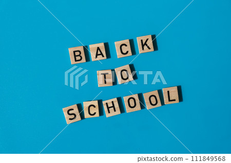 Educational greeting announcement for students and teacher. Saying BACK TO SCHOOL text on wooden blocks on colorful blue background. Top view flat lay Concept of new school year Educational greeting announcement for students and teacher. Saying BACK TO SCHOOL text on wooden blocks on colorful blue background. Top view flat lay Concept of new school year 111849568