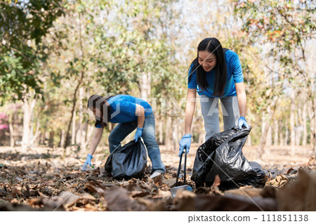 Volunteer collecting plastic trash in the forest. The concept of environmental conservation. Global environmental pollution. Cleaning the forest Volunteer collecting plastic trash in the forest. The concept of environmental conservation. Global environmental pollution. Cleaning the forest 111851138