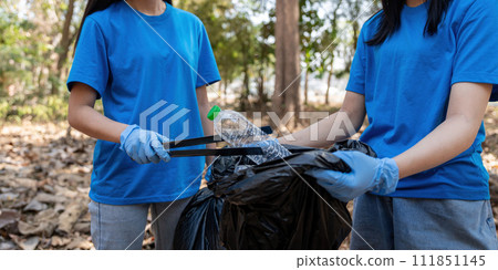 Volunteer collecting plastic trash in the forest. The concept of environmental conservation. Global environmental pollution. Cleaning the forest Volunteer collecting plastic trash in the forest. The concept of environmental conservation. Global environmental pollution. Cleaning the forest 111851145