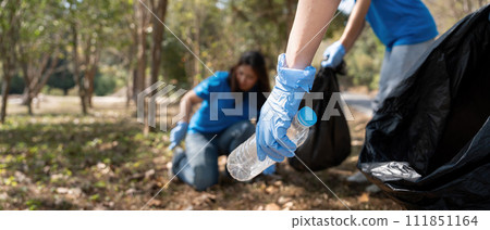Volunteer collecting plastic trash in the forest. The concept of environmental conservation. Global environmental pollution. Cleaning the forest 111851164