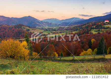 rural landscape of carpathian mountains. beautiful countryside scenery of ukraine in autumn season with fields on the hills and village in the valley 111851412