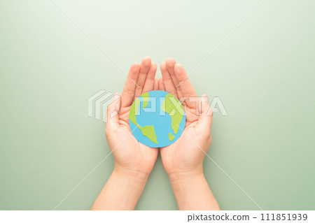 World Earth Day. Human hands holding globe symbol on green background. Concept of green energy, ESG, renewable, sustainable resources and environmental care. Flat layout. World Earth Day. Human hands holding globe symbol on green background. Concept of green energy, ESG, renewable, sustainable resources and environmental care. Flat layout. 111851939