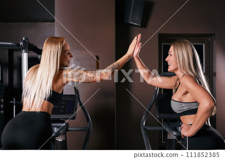 Two attractive sporty women riding exercise bikes during cycling training in gym 111852385