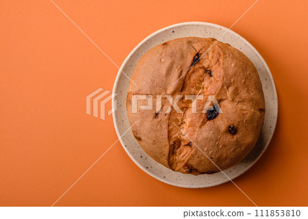 Delicious sweet holiday panettone cake with zest and raisins on a ceramic plate 111853810