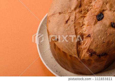 Delicious sweet holiday panettone cake with zest and raisins on a ceramic plate 111853811
