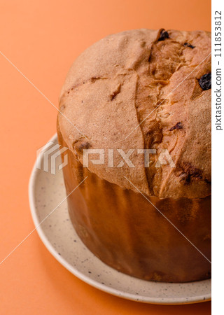 Delicious sweet holiday panettone cake with zest and raisins on a ceramic plate 111853812