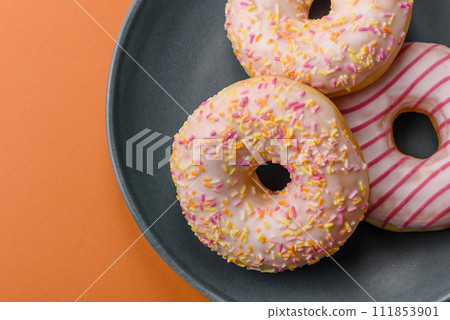 Delicious sweet bright donuts with cream on a plain background 111853901