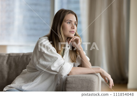 Positive dreamy pretty woman resting on comfortable sofa 111854048