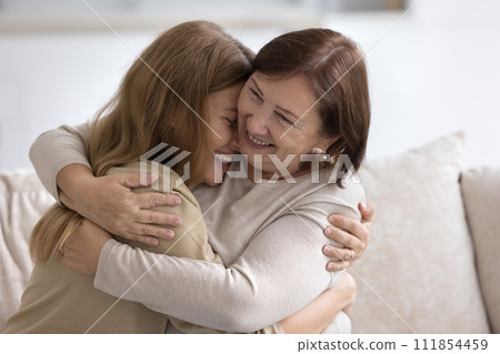 Happy cheerful older retired mom hugging joyful adult child Happy cheerful older retired mom hugging joyful adult child 111854459