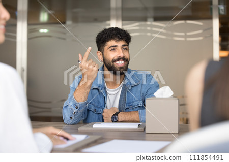 Cheerful handsome Arab entrepreneur man speaking to business partners Cheerful handsome Arab entrepreneur man speaking to business partners 111854491