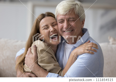 Happy laughing millennial woman cuddling tightly mature dad Happy laughing millennial woman cuddling tightly mature dad 111854515