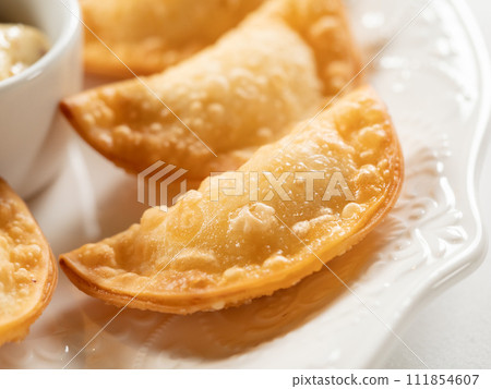 Hot Appetizers with Mini Chebureki and sauces Isolated on white table background. Restaurant Starter Menu with Crispy Burnt Turnovers, Pies or Samosa with Spicy Sause Close Up Hot Appetizers with Mini Chebureki and sauces Isolated on white table background. Restaurant Starter Menu with Crispy Burnt Turnovers, Pies or Samosa with Spicy Sause Close Up 111854607