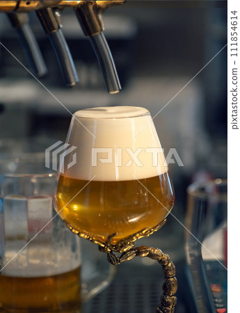 Full glass of fresh light beer near beer tap in pub. Perfect for beer enthusiasts and bar owners. Beer craft and Octoberfest concept. Vertical. Full glass of fresh light beer near beer tap in pub. Perfect for beer enthusiasts and bar owners. Beer craft and Octoberfest concept. Vertical. 111854614