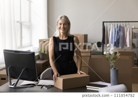 Portrait of happy mature businesswoman posing in warehouse office Portrait of happy mature businesswoman posing in warehouse office 111854782