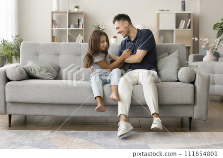 Happy excited young dad tickling cute daughter kid on couch 111854801