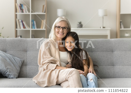Happy positive granny and cute granddaughter girl hugging with love Happy positive granny and cute granddaughter girl hugging with love 111854822