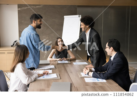 Cheerful office friends shaking hands at corporate business meeting Cheerful office friends shaking hands at corporate business meeting 111854862