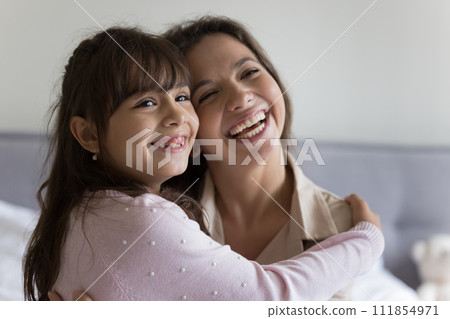 Joyful little girl hugging happy young mother 111854971