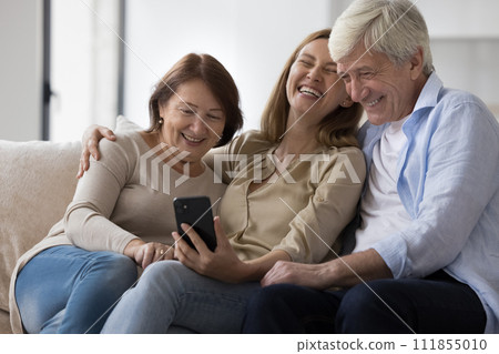 Older parents and adult daughter have fun using mobile application 111855010