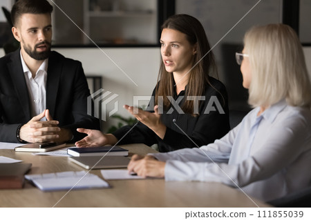 Serious pretty project manager talking to coworkers on brainstorming meeting Serious pretty project manager talking to coworkers on brainstorming meeting 111855039