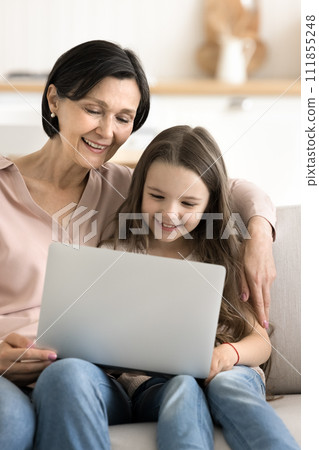 Mature granny and little kid using laptop watching funny cartoons Mature granny and little kid using laptop watching funny cartoons 111855248