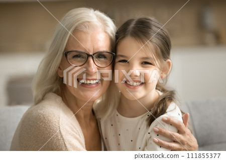 Cheerful senior grandmother and happy little granddaughter home family portrait 111855377