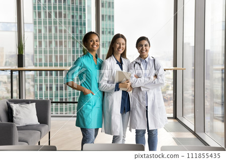Happy confident multiethnic young doctor women in uniforms standing together 111855435