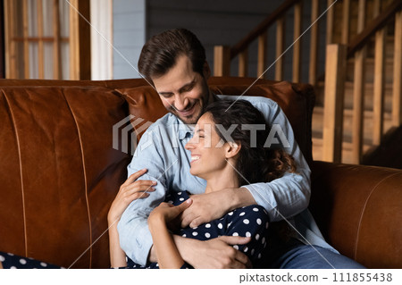Close up happy young couple hugging, relaxing on couch together 111855438