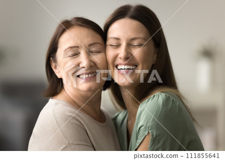 Happy senior mom and adult daughter hugging with cheeks touch Happy senior mom and adult daughter hugging with cheeks touch 111855641