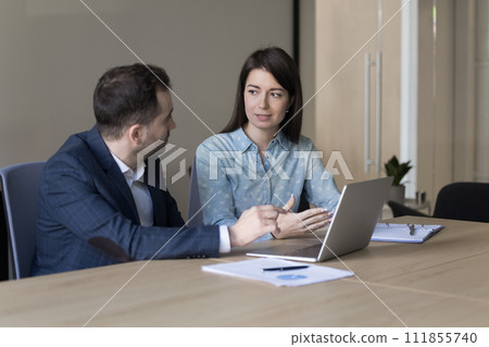 Colleagues engaged in teamwork in office using laptop 111855740