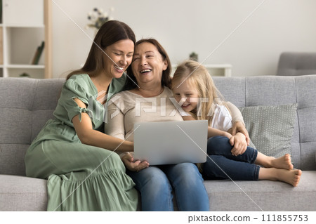 Cheerful mom, grandma and child using laptop together on sofa Cheerful mom, grandma and child using laptop together on sofa 111855753