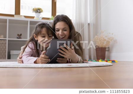 Pretty woman and daughter spend time on internet using tablet Pretty woman and daughter spend time on internet using tablet 111855823