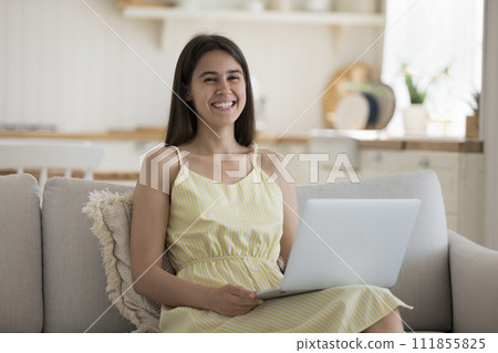 Smiling woman relax at home looking at camera use laptop 111855825