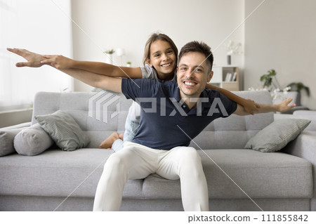 Cheerful playful daddy piggybacking little daughter kid with open hands Cheerful playful daddy piggybacking little daughter kid with open hands 111855842