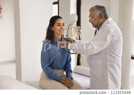 Older Indian doctor man checking heartbeat rate of young patient Older Indian doctor man checking heartbeat rate of young patient 111855846