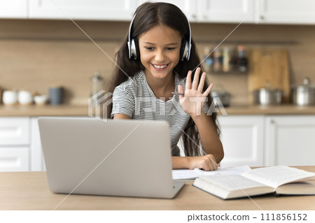Cheerful preteen girl in headphones talking on video conference call 111856152