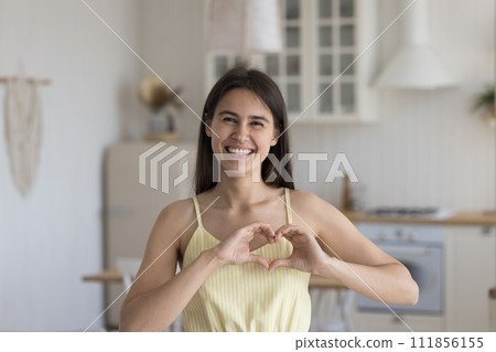 Happy woman looking at camera showing symbol of love 111856155