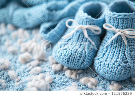 Blue background with knitted baby shoes and copy space. It's a boy backdrop with empty space for text. Baby boy birth announcement. Generative AI. 111856229