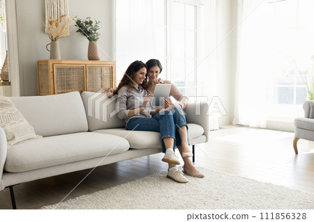 Young adult daughter and mature mother using digital tablet 111856328
