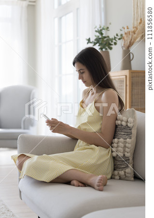 Serious young female spend free time at home with smartphone Serious young female spend free time at home with smartphone 111856580