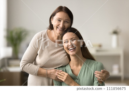 Happy senior mom hugging beautiful young daughter from behind Happy senior mom hugging beautiful young daughter from behind 111856675