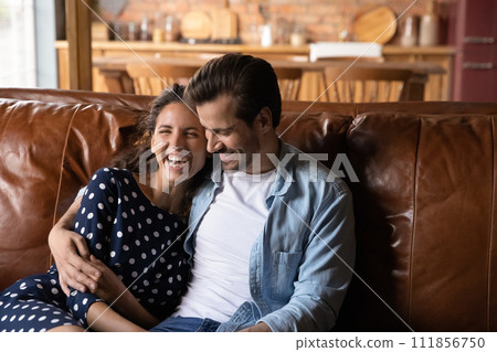 Close up overjoyed millennial couple hugging, relaxing on cozy couch 111856750