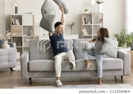 Playful cheerful dad and active daughter child fighting with pillows 111856964