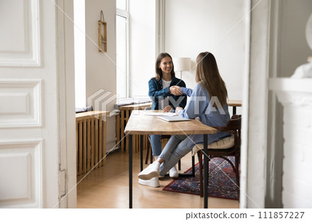 Positive millennial business partner women in casual clothes shaking hands 111857227