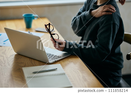 一位肩膀僵硬的年輕女子在辦公桌前工作 111858214