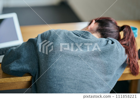 A young woman with a gloomy expression sitting at her desk 111858221