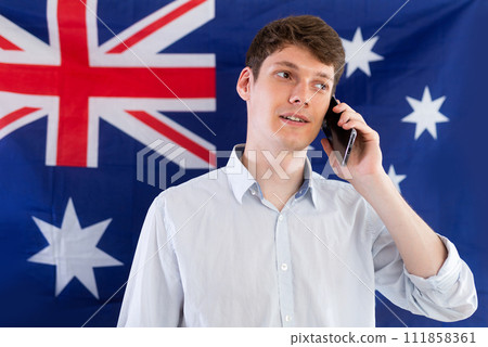 Satisfied student talking on a mobile phone against the background of Australian flag 111858361