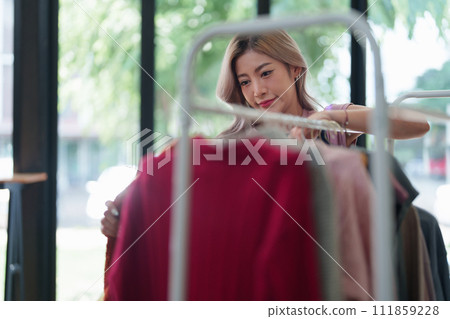 Portrait Of Asian Female Owner Of Fashion Store Checking Stock In Clothing Store With using notebook successful happy smile at small business, sme or ecommerce concepts. Portrait Of Asian Female Owner Of Fashion Store Checking Stock In Clothing Store With using notebook successful happy smile at small business, sme or ecommerce concepts. 111859228