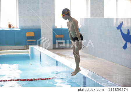 A boy in a swimming cap is jumping in a sports pool. A boy in a swimming cap is jumping in a sports pool. 111859274